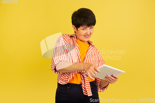 Image of Senior woman isolated on yellow background. Tech and joyful elderly lifestyle concept