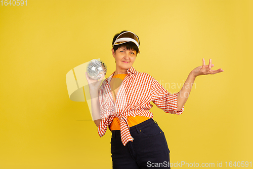 Image of Senior woman isolated on yellow background. Tech and joyful elderly lifestyle concept