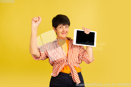 Image of Senior woman isolated on yellow background. Tech and joyful elderly lifestyle concept