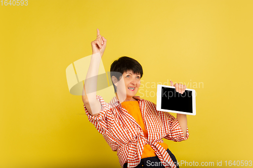 Image of Senior woman isolated on yellow background. Tech and joyful elderly lifestyle concept