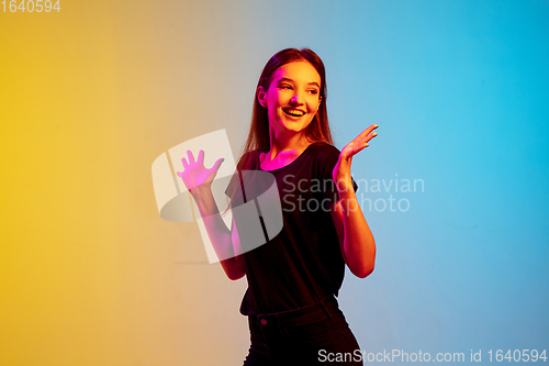 Image of Young caucasian woman\'s portrait on gradient blue-yellow studio background in neon light