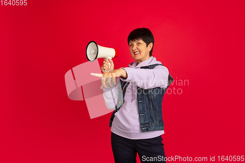 Image of Senior woman isolated on red background. Tech and joyful elderly lifestyle concept