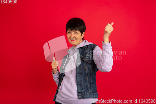 Image of Senior woman isolated on red background. Tech and joyful elderly lifestyle concept