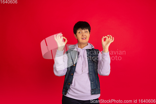 Image of Senior woman isolated on red background. Tech and joyful elderly lifestyle concept