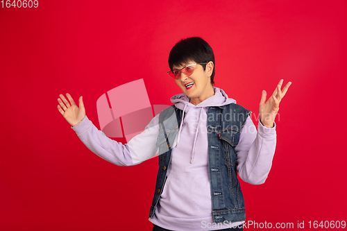 Image of Senior woman isolated on red background. Tech and joyful elderly lifestyle concept