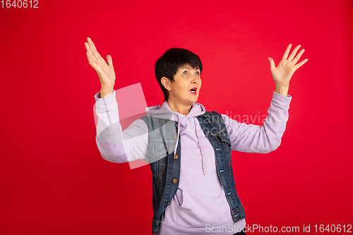 Image of Senior woman isolated on red background. Tech and joyful elderly lifestyle concept