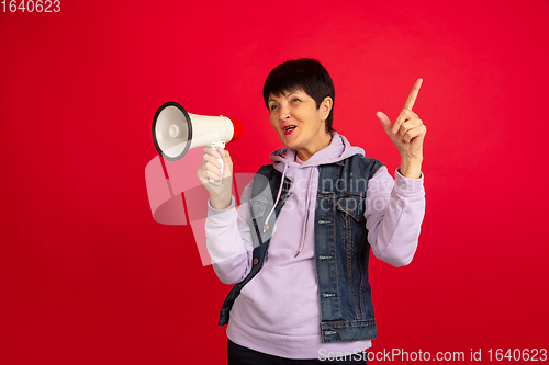 Image of Senior woman isolated on red background. Tech and joyful elderly lifestyle concept