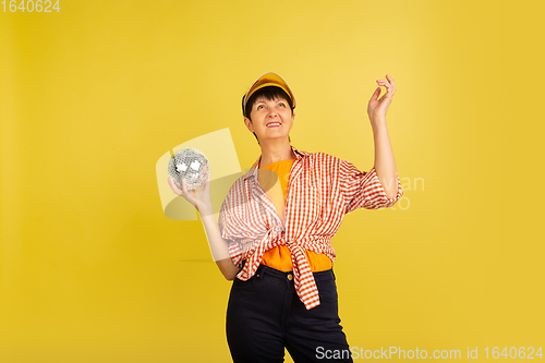 Image of Senior woman isolated on yellow background. Tech and joyful elderly lifestyle concept