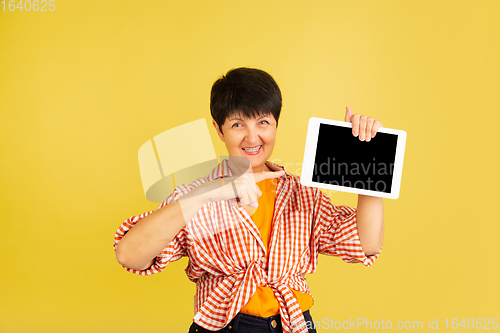 Image of Senior woman isolated on yellow background. Tech and joyful elderly lifestyle concept