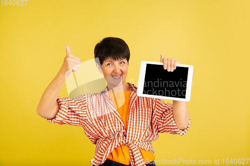 Image of Senior woman isolated on yellow background. Tech and joyful elderly lifestyle concept