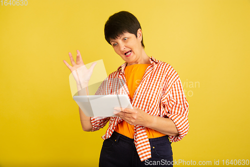 Image of Senior woman isolated on yellow background. Tech and joyful elderly lifestyle concept