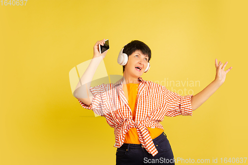 Image of Senior woman isolated on yellow background. Tech and joyful elderly lifestyle concept