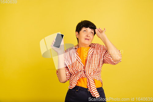 Image of Senior woman isolated on yellow background. Tech and joyful elderly lifestyle concept