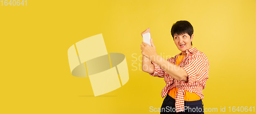 Image of Senior woman isolated on yellow background. Tech and joyful elderly lifestyle concept