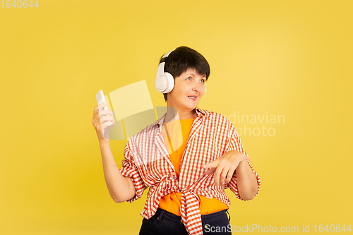 Image of Senior woman isolated on yellow background. Tech and joyful elderly lifestyle concept