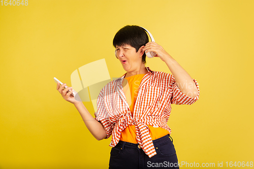 Image of Senior woman isolated on yellow background. Tech and joyful elderly lifestyle concept