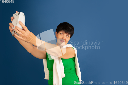 Image of Senior woman isolated on blue background. Tech and joyful elderly lifestyle concept