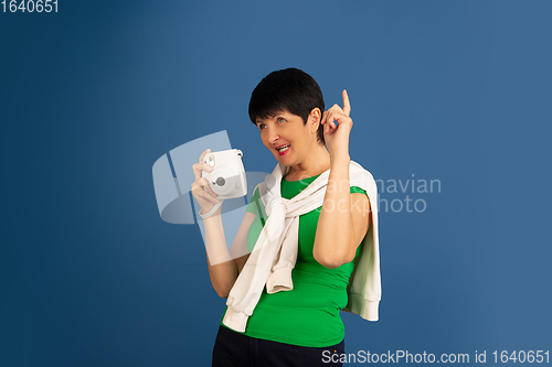 Image of Senior woman isolated on blue background. Tech and joyful elderly lifestyle concept