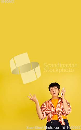 Image of Senior woman isolated on yellow background. Tech and joyful elderly lifestyle concept