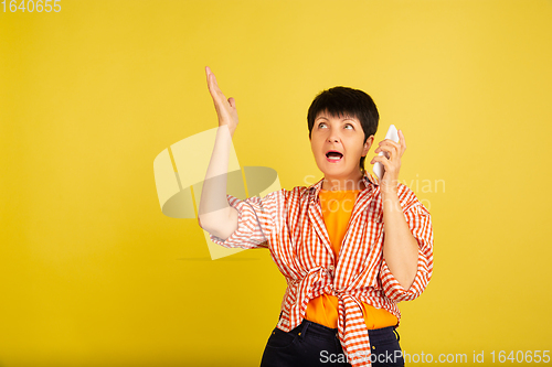 Image of Senior woman isolated on yellow background. Tech and joyful elderly lifestyle concept