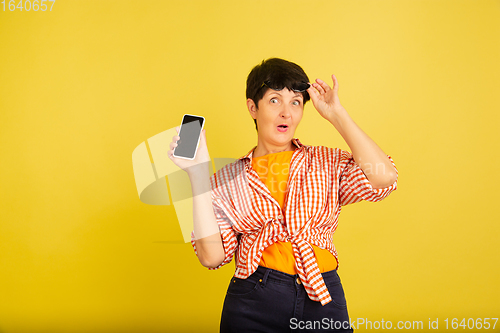 Image of Senior woman isolated on yellow background. Tech and joyful elderly lifestyle concept