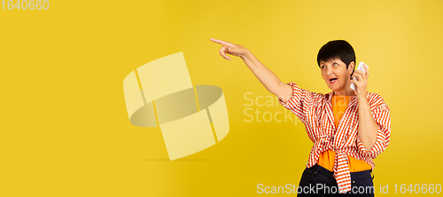 Image of Senior woman isolated on yellow background. Tech and joyful elderly lifestyle concept