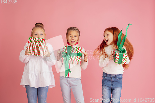 Image of Giving and getting presents on Christmas holidays. Group of happy smiling children having fun isolated on pink studio background