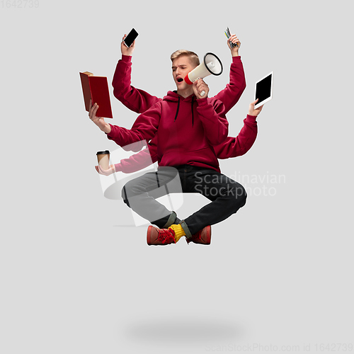 Image of Handsome multi-armed student levitating isolated on grey studio background with equipment