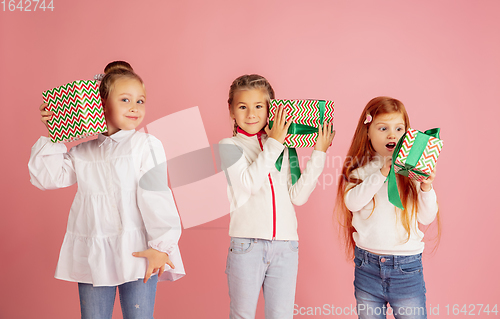 Image of Giving and getting presents on Christmas holidays. Group of happy smiling children having fun isolated on pink studio background