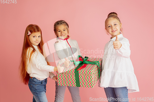 Image of Giving and getting presents on Christmas holidays. Group of happy smiling children having fun isolated on pink studio background