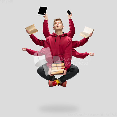 Image of Handsome multi-armed student levitating isolated on grey studio background with equipment