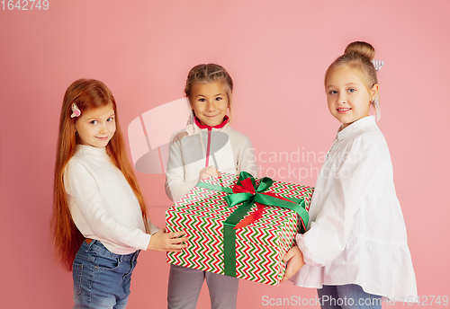 Image of Giving and getting presents on Christmas holidays. Group of happy smiling children having fun isolated on pink studio background