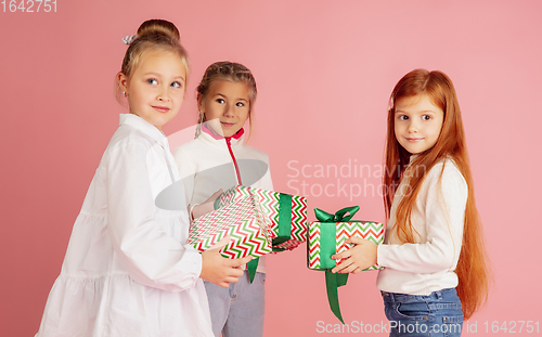 Image of Giving and getting presents on Christmas holidays. Group of happy smiling children having fun isolated on pink studio background