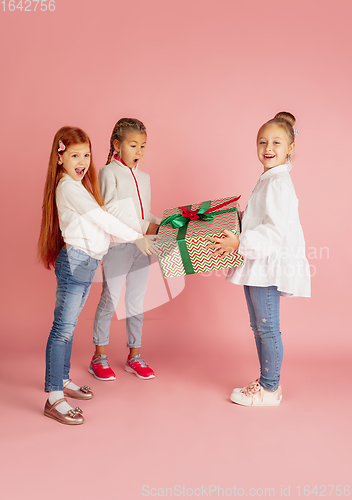 Image of Giving and getting presents on Christmas holidays. Group of happy smiling children having fun isolated on pink studio background