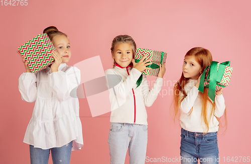 Image of Giving and getting presents on Christmas holidays. Group of happy smiling children having fun isolated on pink studio background