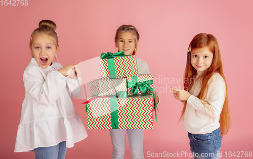 Image of Giving and getting presents on Christmas holidays. Group of happy smiling children having fun isolated on pink studio background