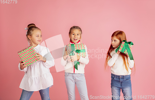 Image of Giving and getting presents on Christmas holidays. Group of happy smiling children having fun isolated on pink studio background