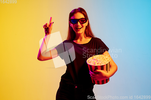 Image of Young caucasian woman\'s portrait on gradient blue-yellow studio background in neon light