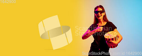 Image of Young caucasian woman\'s portrait on gradient blue-yellow studio background in neon light