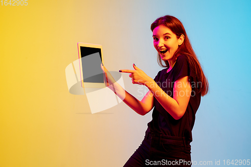 Image of Young caucasian woman\'s portrait on gradient blue-yellow studio background in neon light