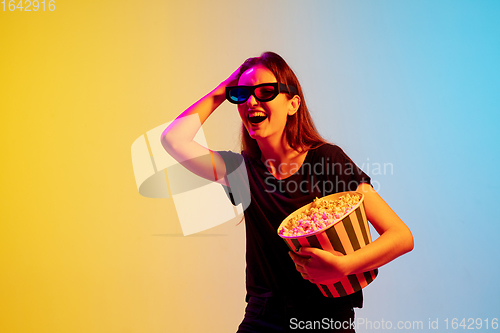 Image of Young caucasian woman\'s portrait on gradient blue-yellow studio background in neon light