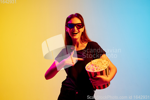 Image of Young caucasian woman\'s portrait on gradient blue-yellow studio background in neon light