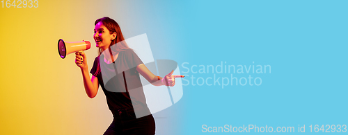 Image of Young caucasian woman\'s portrait on gradient blue-yellow studio background in neon light