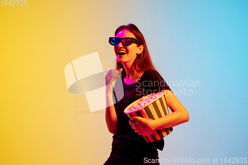 Image of Young caucasian woman\'s portrait on gradient blue-yellow studio background in neon light