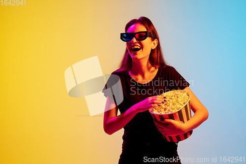 Image of Young caucasian woman\'s portrait on gradient blue-yellow studio background in neon light