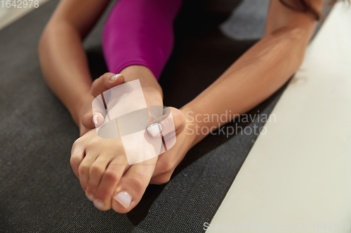 Image of Close up of beautiful young woman working out indoors, doing yoga exercise on gray mat, details