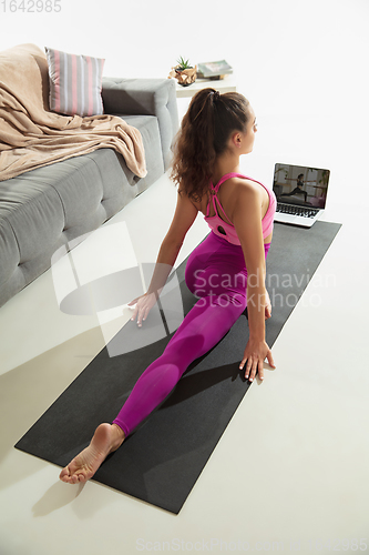 Image of Beautiful young woman working out indoors, doing yoga exercise on gray mat at home