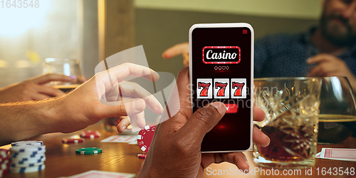 Image of Online gambling, casino concept. Hand holding device with lottery, casino cover