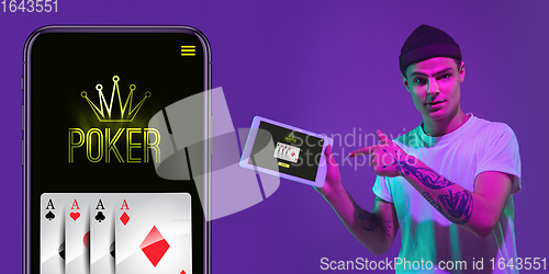 Image of Online gambling, casino concept. Young man holding devices with lottery, casino cover in neon light