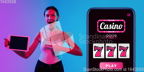 Image of Online gambling, casino concept. Young woman holding devices with lottery, casino cover in neon light